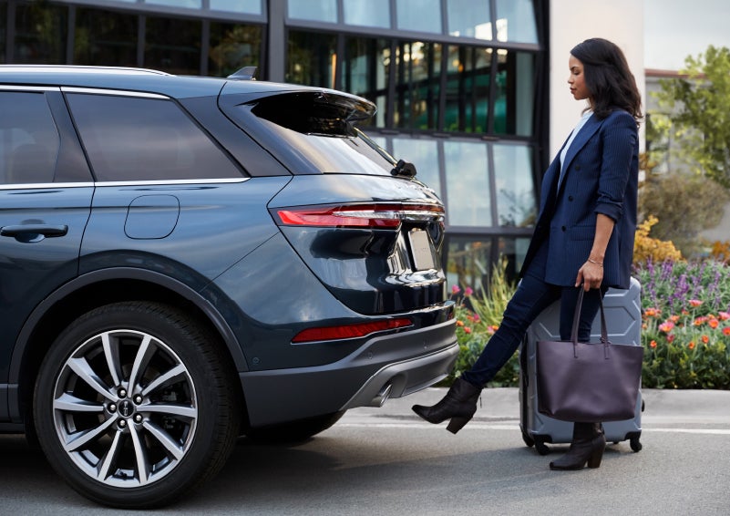 A woman with luggage and a bag opens the available hands-free liftgate by kicking her foot under the bumper | Empire Lincoln in Abingdon VA