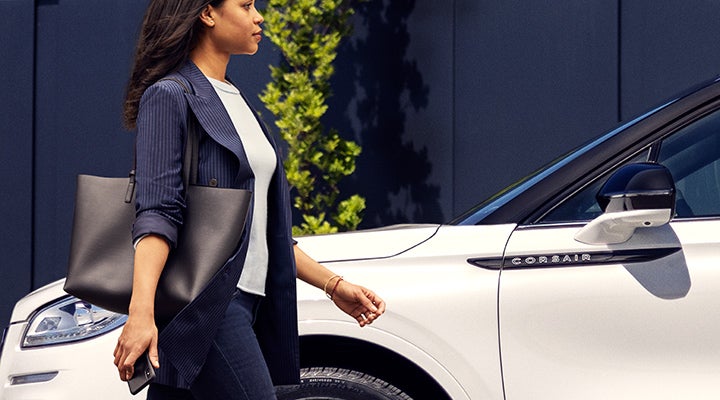 A woman approaches a 2024 Lincoln Corsair® SUV while holding a smartphone. | Empire Lincoln in Abingdon VA