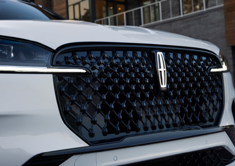 The black grille of a white 2025 Lincoln Aviator® SUV is shown with its fog lights on. | Empire Lincoln in Abingdon VA