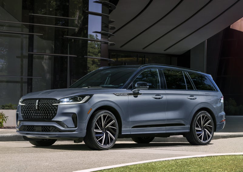 A gray 2025 Lincoln Aviator® SUV is parked outside a modern building showcasing the driver’s side of the vehicle. | Empire Lincoln in Abingdon VA