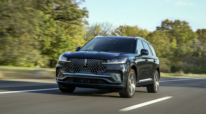 A 2026 Lincoln Black Label™ Aviator® SUV is being driven down a road lined with trees. | Empire Lincoln in Abingdon VA